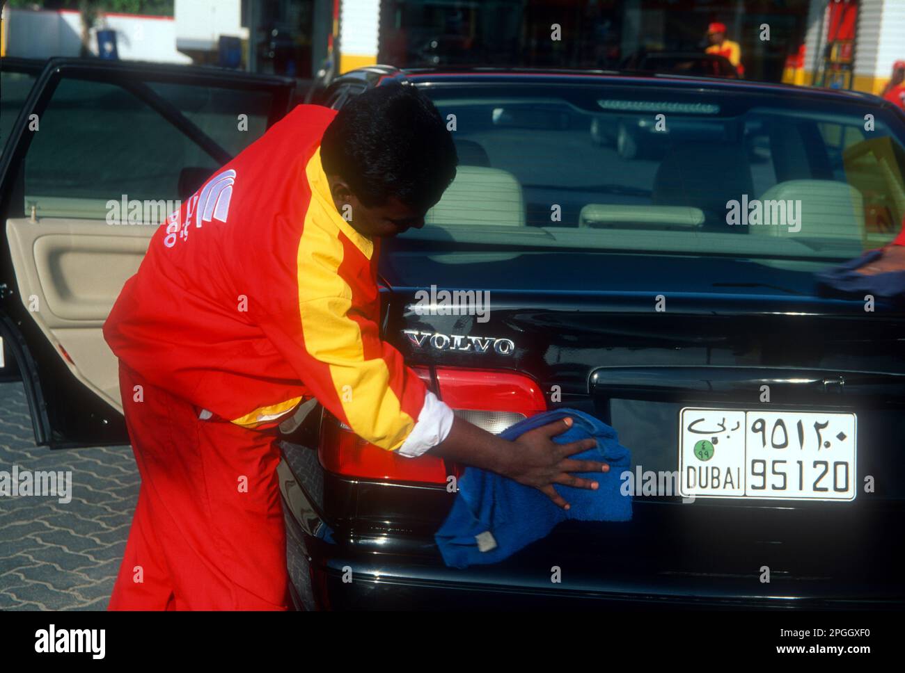 Wanderarbeiter aus dem Subkontinent Indo-Pak, der ein Auto in Dubai, Vereinigte Arabische Emirate, reinigt Stockfoto