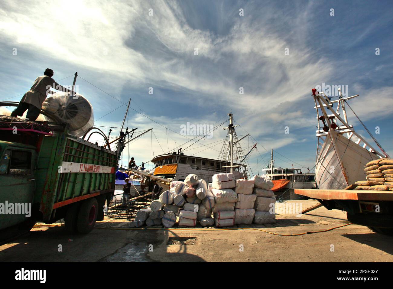 Eine Szene, die Fracht, Lastwagen, traditionelle pinisi-Schiffe und Arbeiter an einem glühend heißen Tag im Hafen von Paotere in Ujung Tanah, Makassar, South Sulawesi, Indonesien zeigt. Laut dem Bericht des Weltklimarates (Intergovernmental Panel on Climate Change, IPCC) aus dem Jahr 2023 mit dem Titel „Climate Change 2022: Impacts, Adaptation and Vulnerability“ (Klimaänderung: Auswirkungen, Anpassung und Verwundbarkeit) werden Arbeitnehmer im Freien zunehmend Hitzestress ausgesetzt und ihre arbeitskapazität verringert. Der Klimawandel wird Outdoor-Arbeitnehmer zunehmend Hitzestress aussetzen und die arbeitskapazität verringern, so der Bericht aus dem Jahr 2023, der von der... Stockfoto