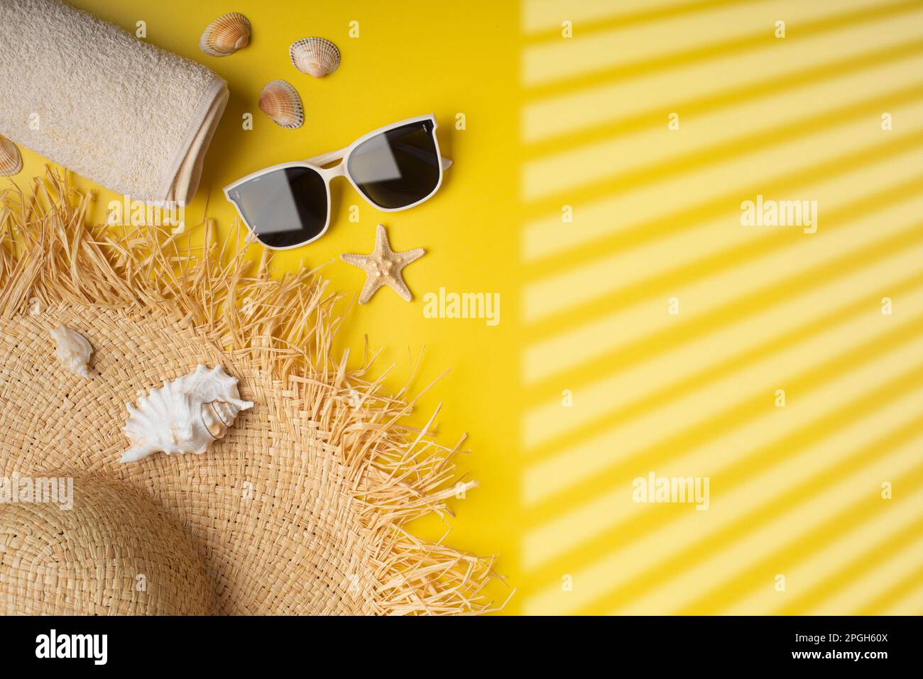 Handtuch Strohhut Sonnenbrillen und Seesterne auf gelbem Hintergrund Reiseplanungsmodell Stockfoto