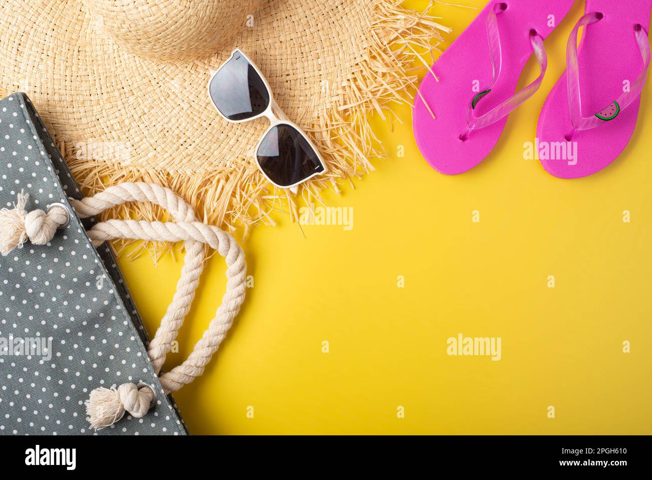 Flip-Flops Strohhut Sonnenbrillen und Strandtasche auf gelbem Hintergrund Reiseplanungsmodell Stockfoto