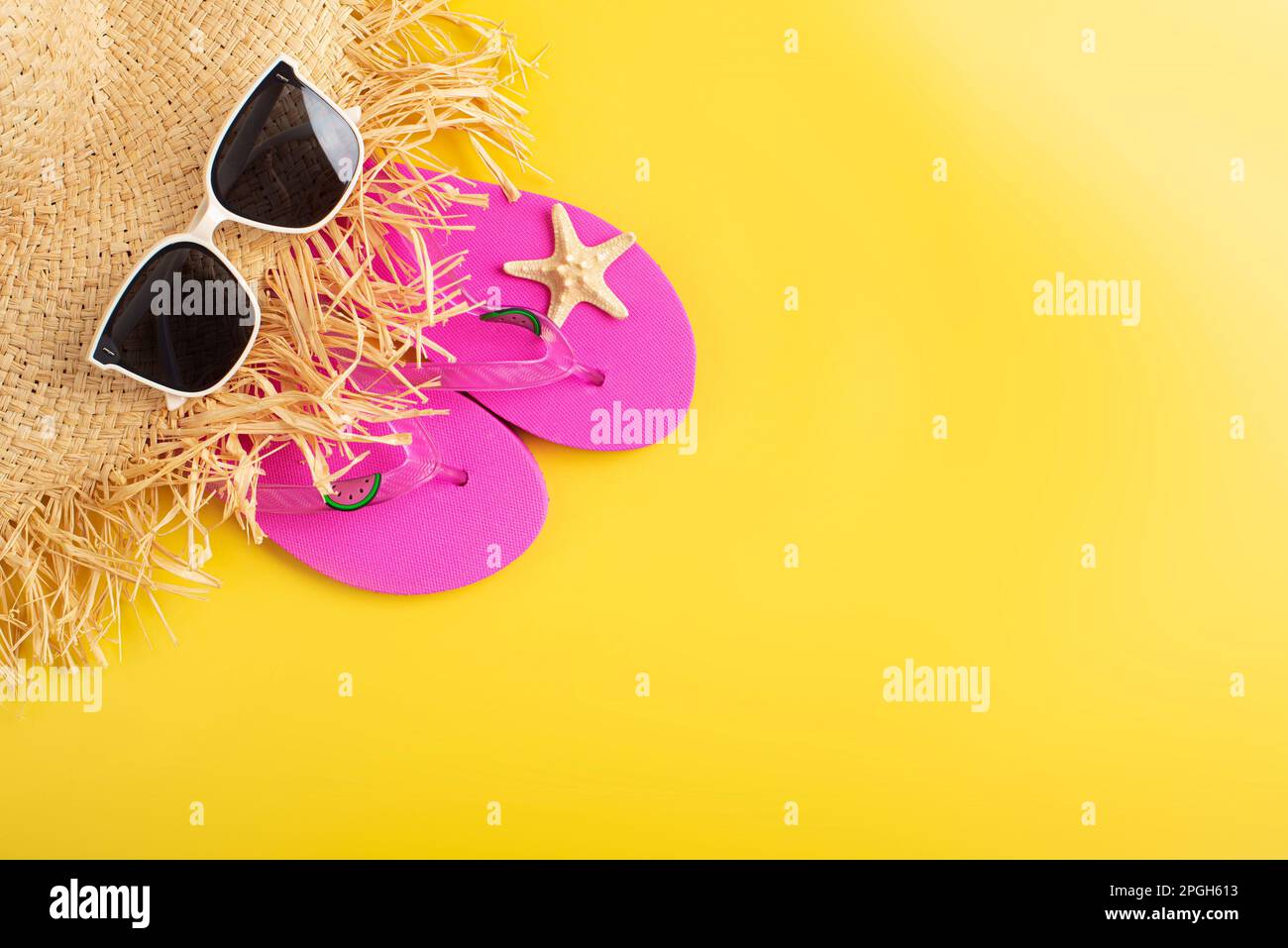 Flip Flops Strohhut Sonnenbrillen und Seesterne auf gelbem Hintergrund Reiseplanungsmodell Stockfoto