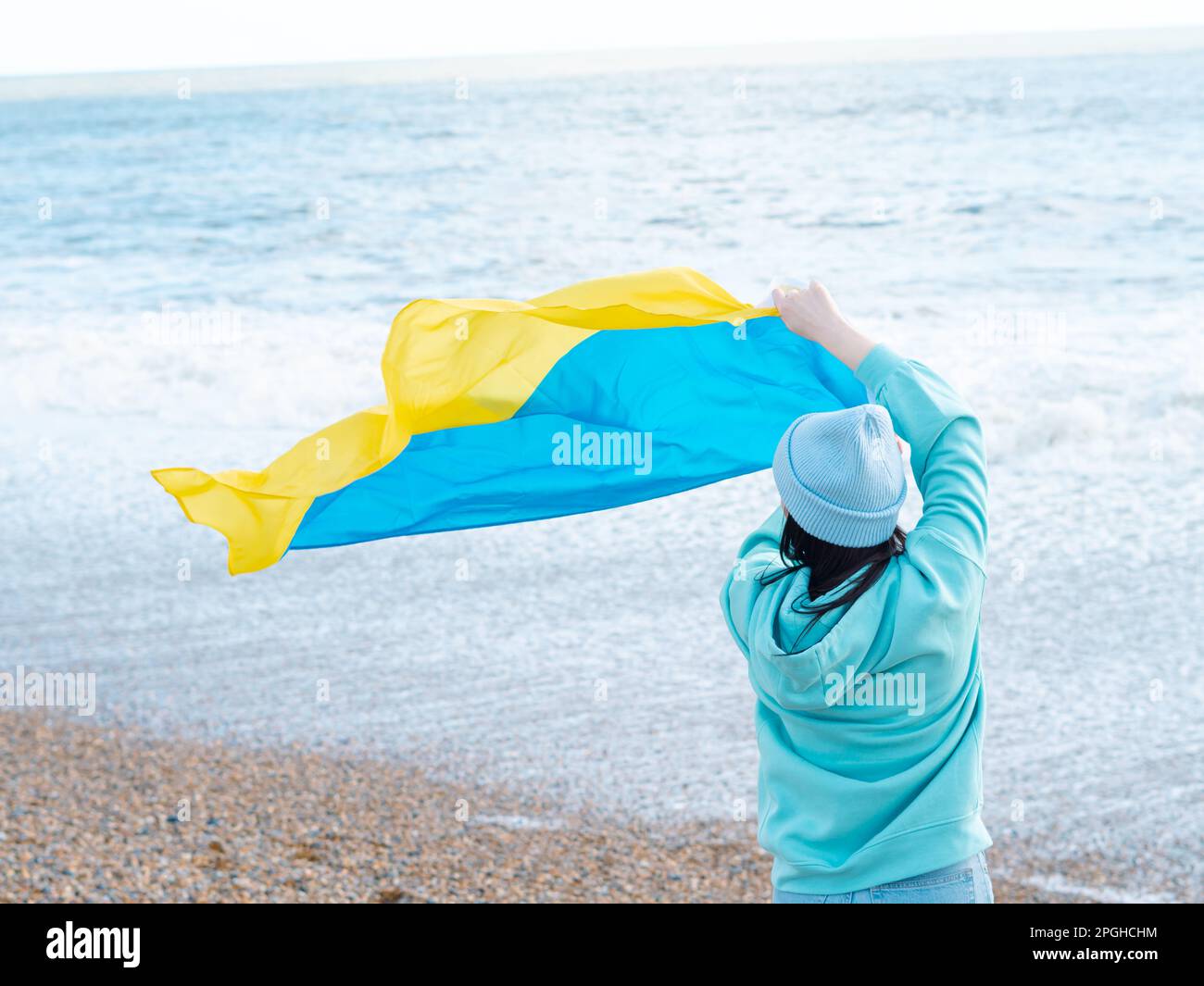 Braune Frau in blauem Hoodie und blauem Hut mit ukrainischer Nationalflagge, patriotisches Konzept Stockfoto