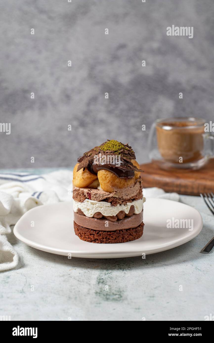 Mehrschichtiger Profiteroles-Kuchen. Schlagsahne, Schokolade und Pistazienkuchen. Stockfoto