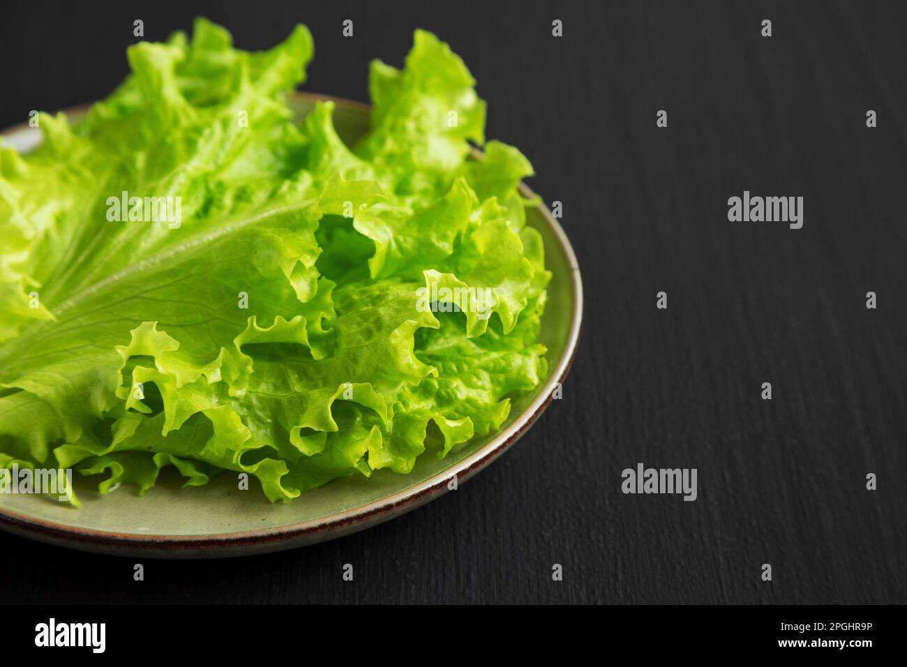 Roher grüner Blattsalat auf einem Teller, Blick aus niedrigem Winkel. Nahaufnahme. Stockfoto