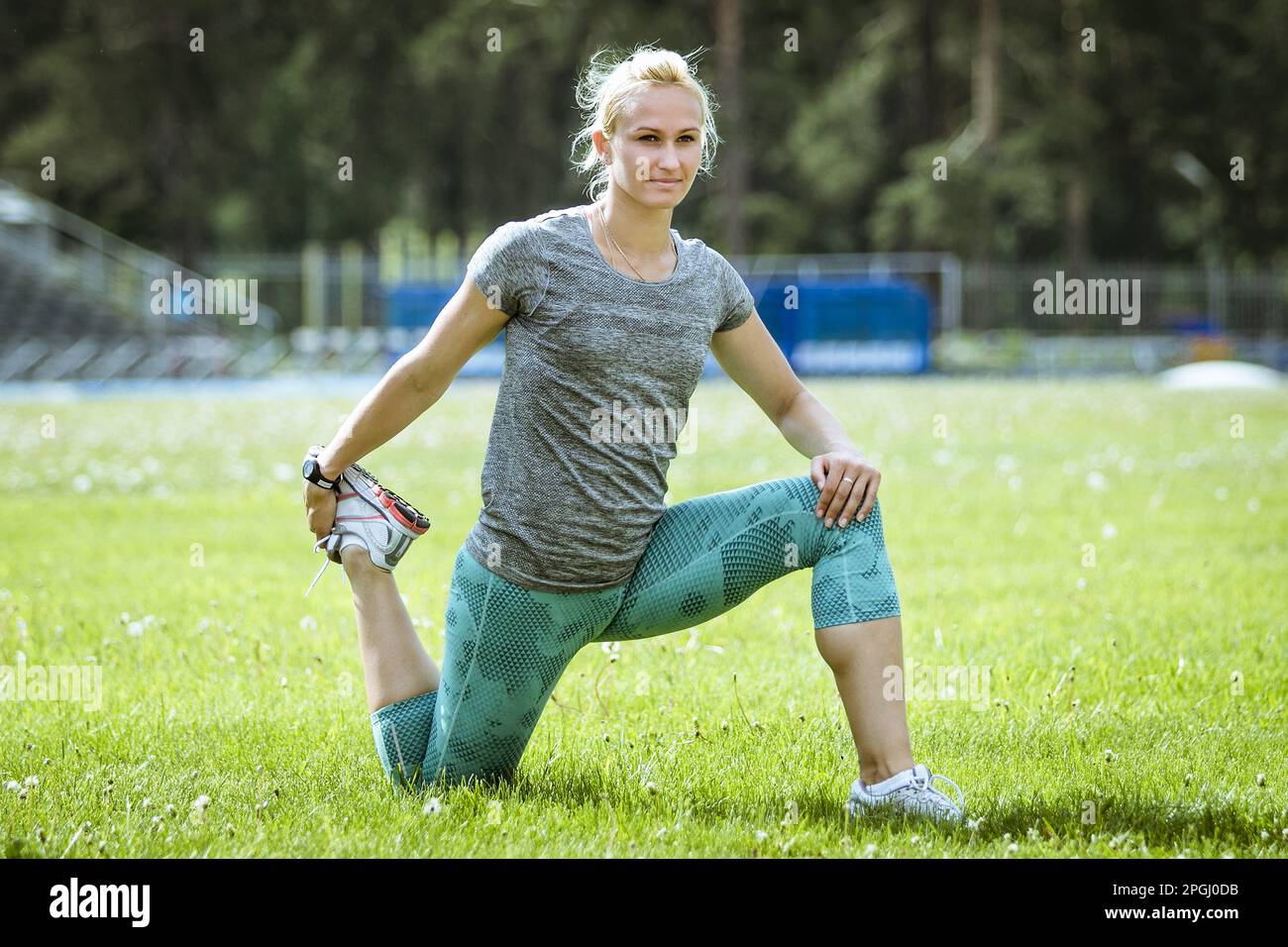 Sportlerin, die auf dem Green Field Stretching macht und sich vor dem sportlichen Training aufwärmt Stockfoto