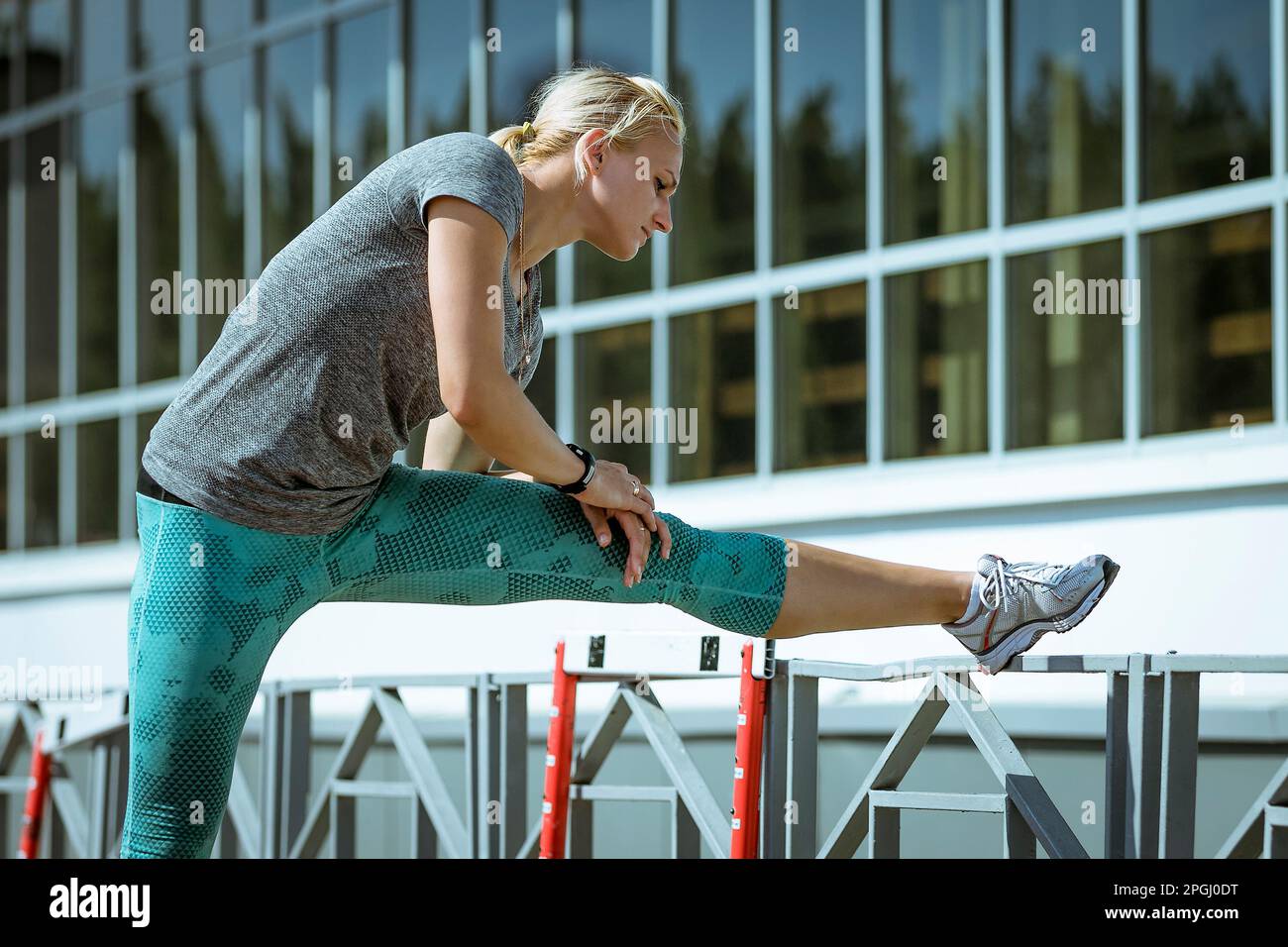 Sportlerin, die Dehnübungen macht, sich nach vorne zum Bein neigt und sich vor dem Sporttraining aufwärmt Stockfoto