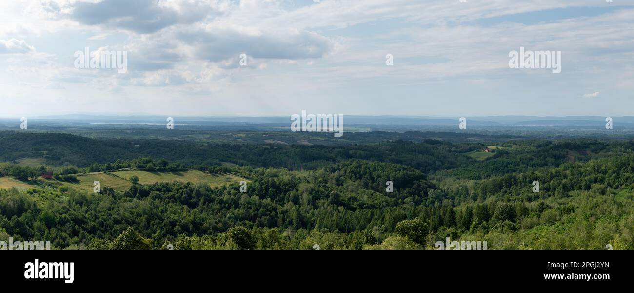 Hügeliges Landschaftspanorama, weit entferntes Tal voller Dunst, verstreute Dörfer und üppige Wälder Stockfoto