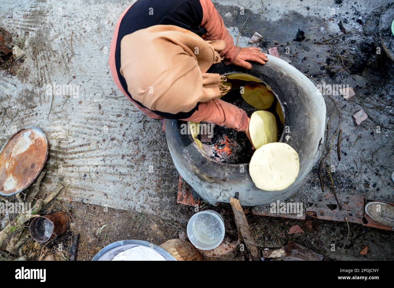 Tunis, Tunesien. 22. März 2023. Tunis, Tunesien, 22. März 2023. Eine tunesische Frau backt das Tabouna-Brot in einem traditionellen Tonofen, bevor sie es auf einem Markt in Tunis verkauft. Tabouna ist ein altes tunesisches Brot aus Weizen-, Grieß- oder Gerstenmehl, das an den Wänden eines traditionellen Terrakotta-Ofens gekocht wird. Tabouna ist besonders beliebt während des heiligen muslimischen Monats Ramadan (Kreditbild: © Hasan mrad/IMAGESLIVE via ZUMA Press Wire). Nicht für den kommerziellen GEBRAUCH! Stockfoto