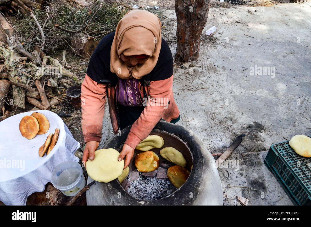 Tunis, Tunesien. 22. März 2023. Tunis, Tunesien, 22. März 2023. Eine tunesische Frau backt das Tabouna-Brot in einem traditionellen Tonofen, bevor sie es auf einem Markt in Tunis verkauft. Tabouna ist ein altes tunesisches Brot aus Weizen-, Grieß- oder Gerstenmehl, das an den Wänden eines traditionellen Terrakotta-Ofens gekocht wird. Tabouna ist besonders beliebt während des heiligen muslimischen Monats Ramadan (Kreditbild: © Hasan mrad/IMAGESLIVE via ZUMA Press Wire). Nicht für den kommerziellen GEBRAUCH! Stockfoto