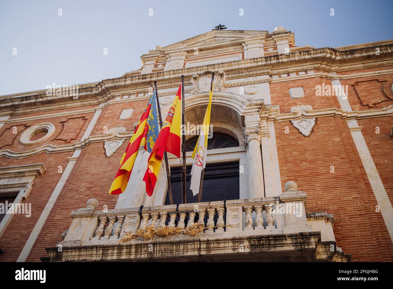 Alte Gebäudewand in den Straßen der Stadt Valencia. Die katalanische und die spanische Flagge flattern im Wind auf einem alten Gebäude. Stockfoto