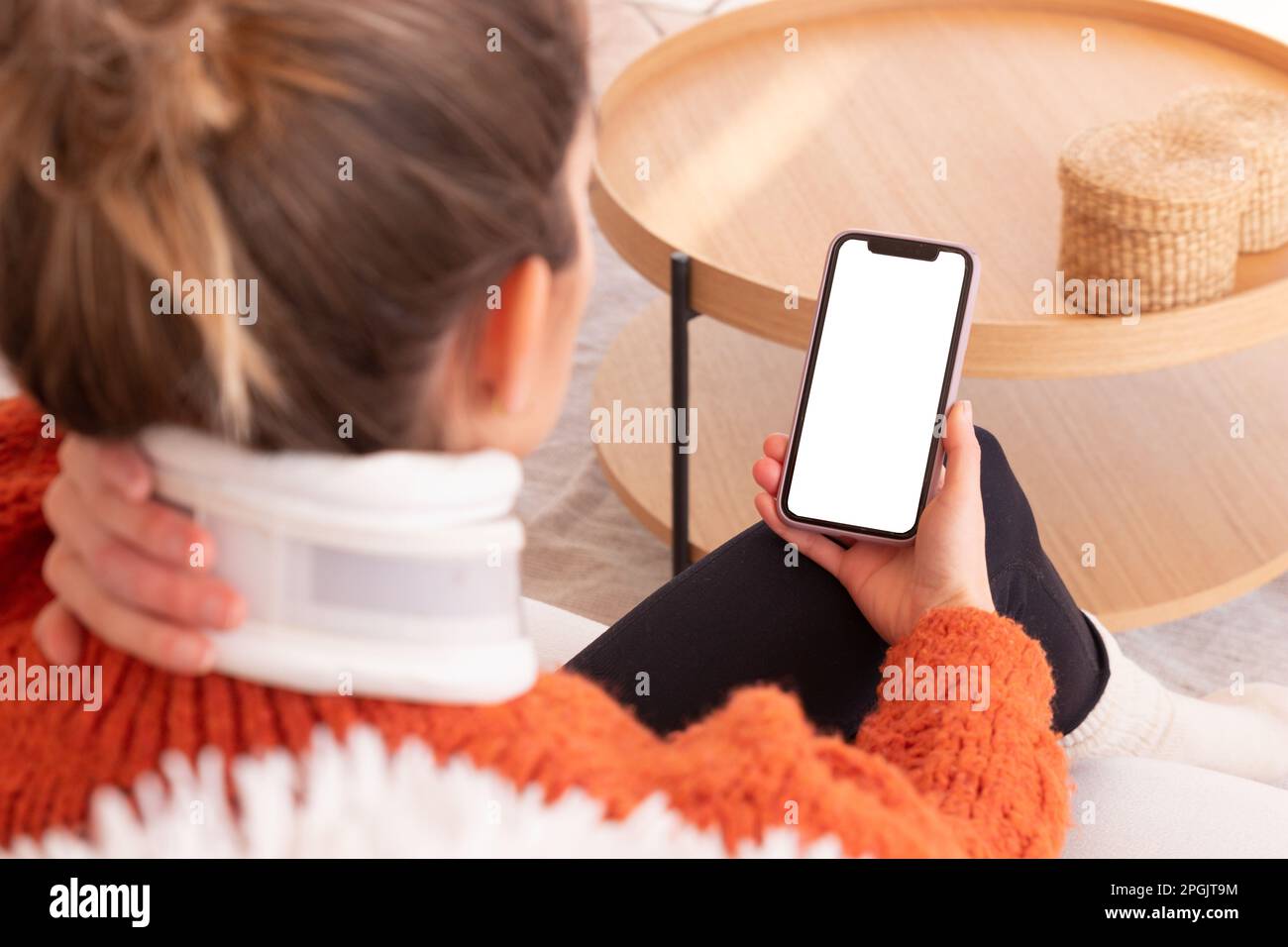 Unerkannte Frau mit Halskragen am Hals diskutiert Probleme mit dem Arzt während einer Online-Sitzung auf dem Smartphone Stockfoto