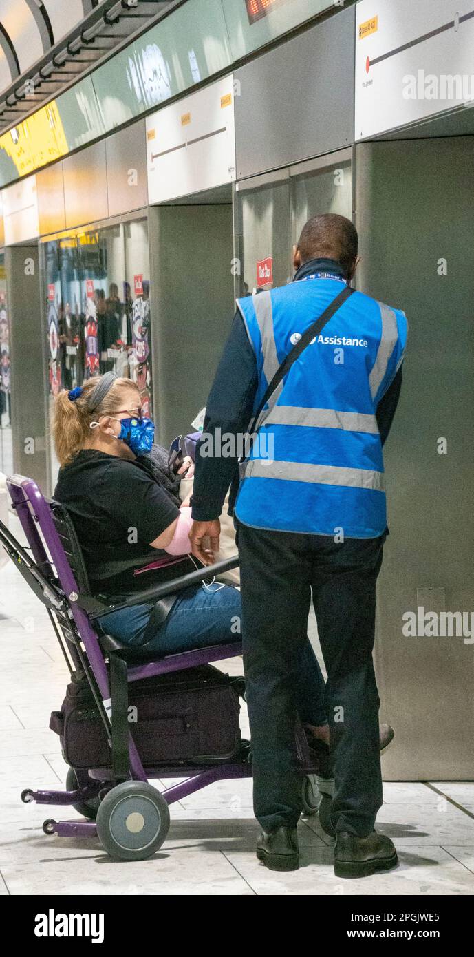 Assistentin, die Frau im Rollstuhlzug zum Terminal 5, Flughafen Heathrow, London, UK, hilft Stockfoto