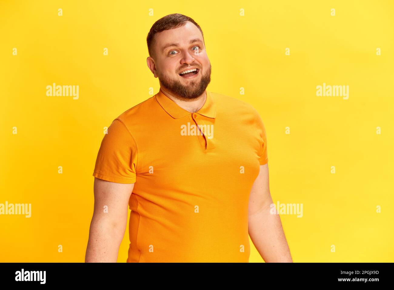 Ein attraktiver Mann, der lächelt und in die Kamera schaut, mit positivem Gesichtsausdruck auf gelbem Hintergrund. Schließen Stockfoto
