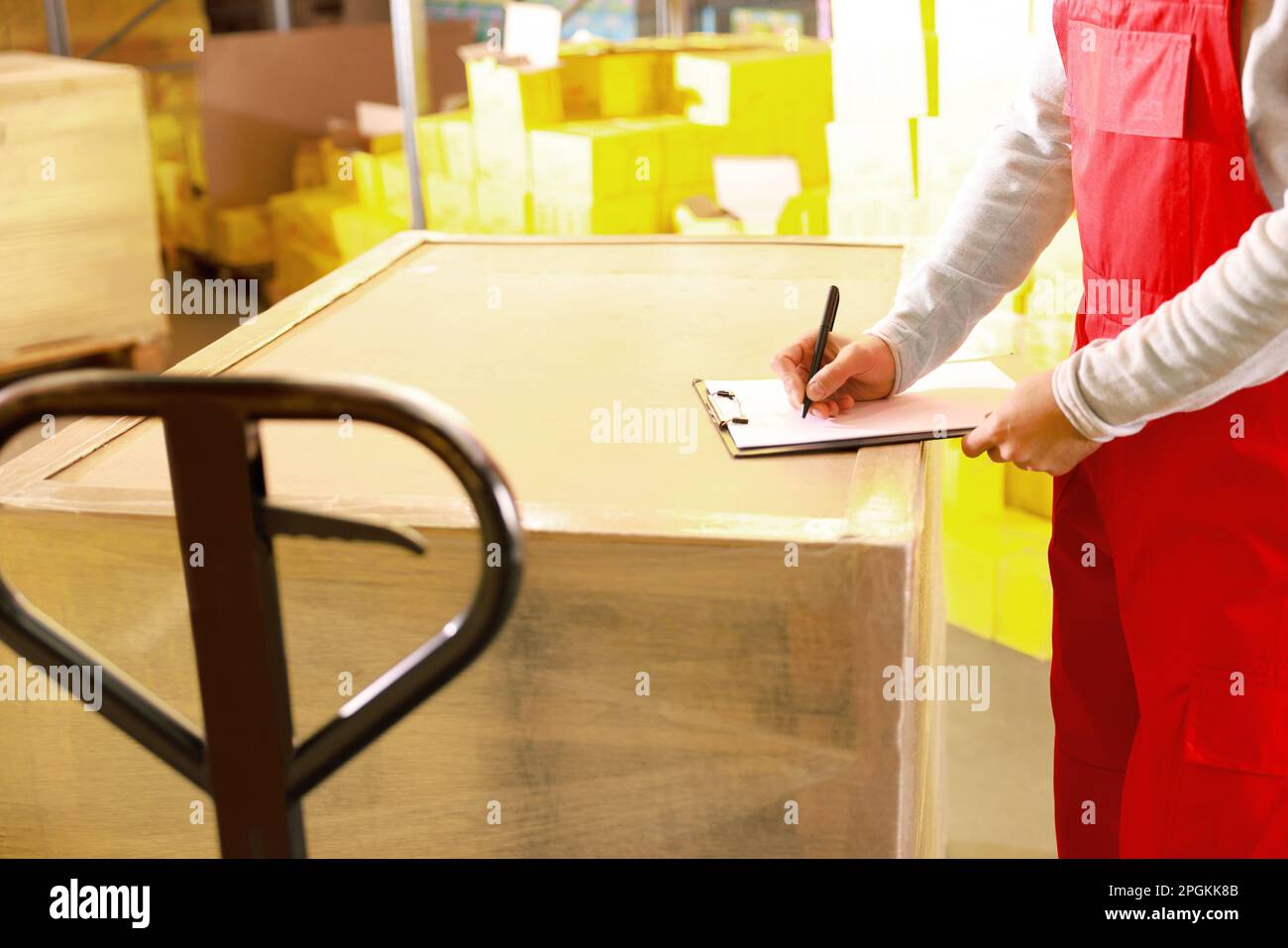 Arbeiter mit Klemmbrett in der Nähe von verpackten Paletten im Lager, Nahaufnahme. Logistikkonzept Stockfoto