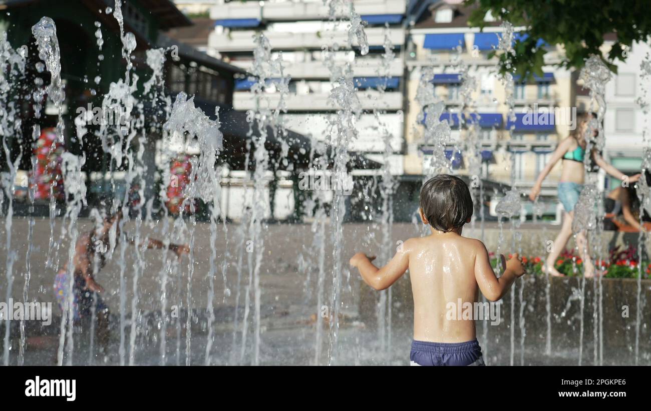 Fröhliches Kind, das Spaß bei Wasserpark Jets in 120fps Slow Motion während des heißen Sommertags hat Stockfoto