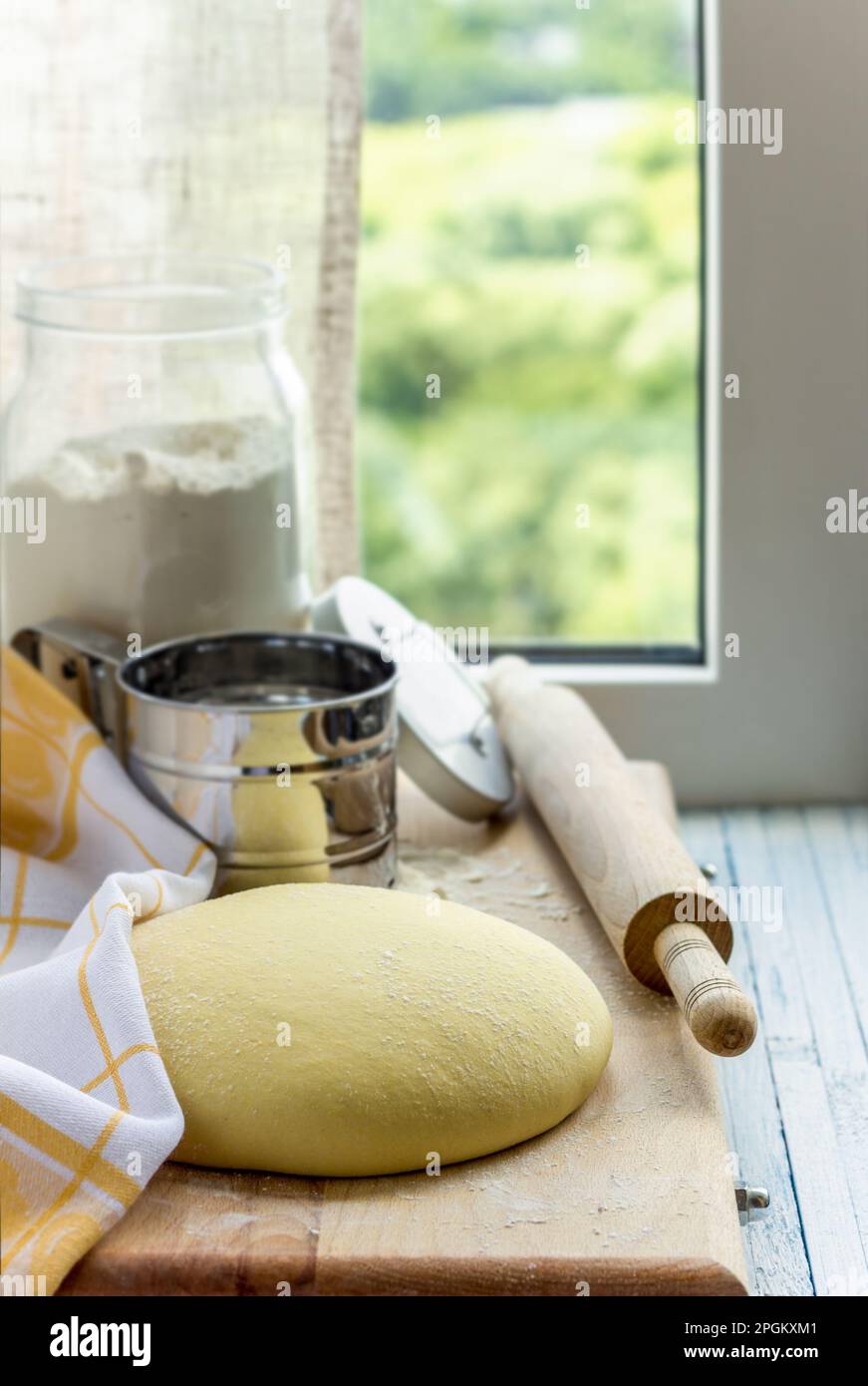 Ich koche Maistortillas oder Brötchen. Roher geschnittener Teig auf einer Holzplatte vor dem Hintergrund des Fensters. Selektiver Fokus, Vorderansicht. Hausgemachte gesunde Fo Stockfoto