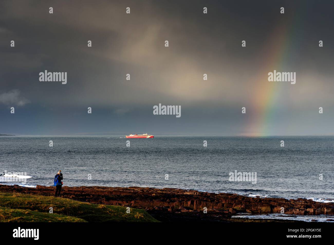 Die Fähre Gills Bay nach Orkney, der MV Alfred, unter stürmischem Himmel und Regenbogen, auf dem Pentland Firth, nahe John O'Groats, Caithness, Schottland, Großbritannien. Stockfoto