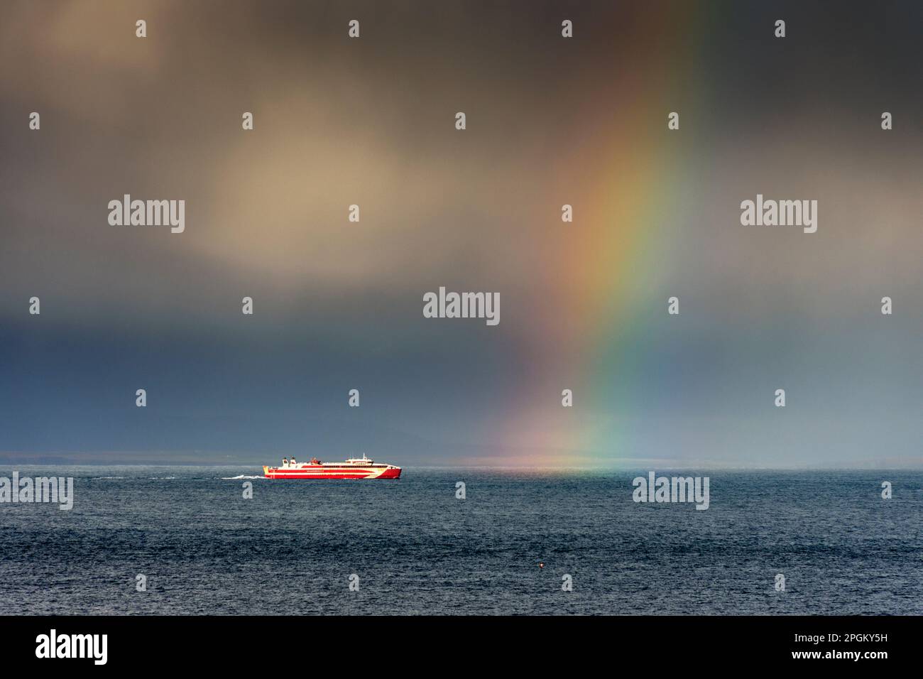 Die Fähre Gills Bay nach Orkney, der MV Alfred, unter stürmischem Himmel und Regenbogen, auf dem Pentland Firth, nahe John O'Groats, Caithness, Schottland, Großbritannien. Stockfoto