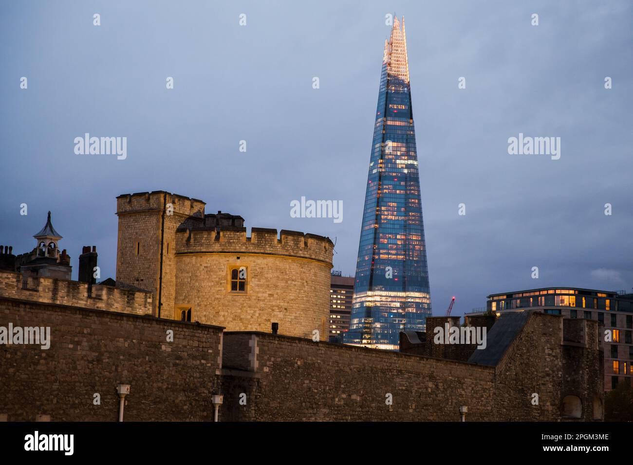 Stadtfoto von London bei Nacht mit Steinwänden des Tower of London und dem Wolkenkratzer Business im Hintergrund Stockfoto