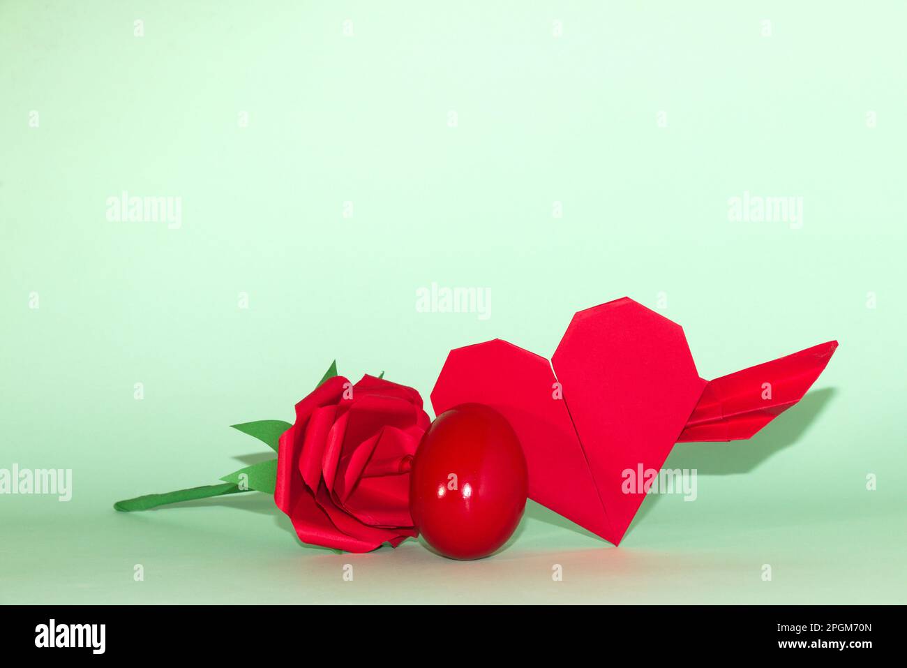 Rotes Ei mit Blumen und Herz, grüner Hintergrund, kreatives Weihnachtsdesign Stockfoto