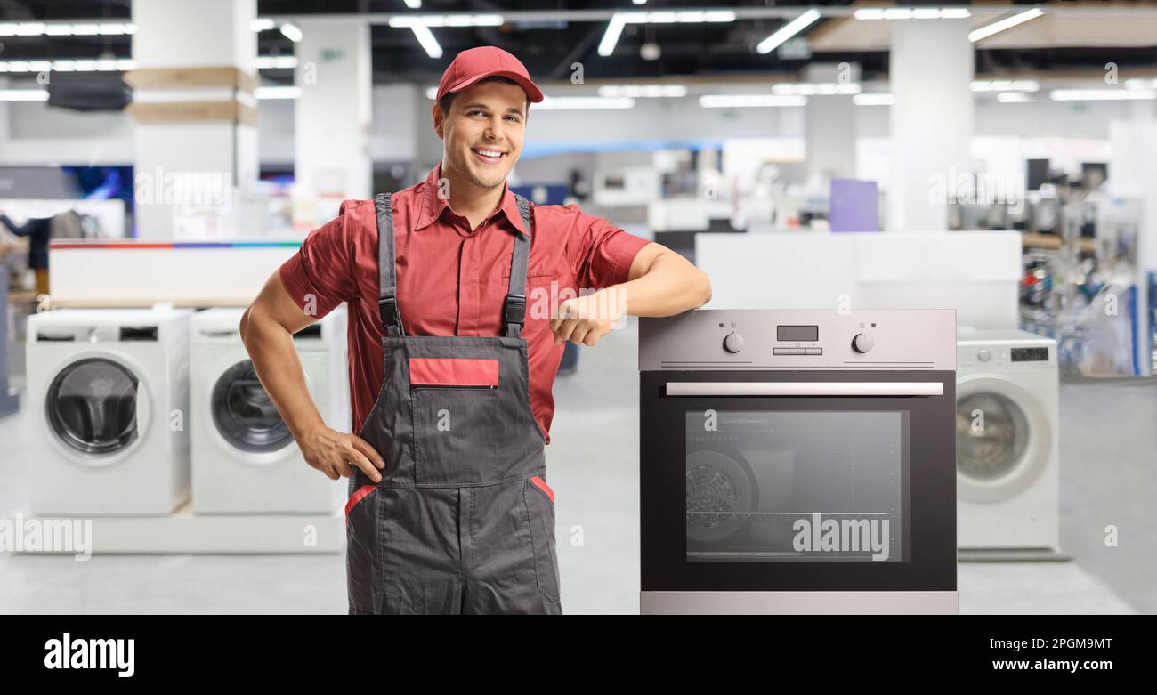 Reparaturarbeiter in einem Elektrowerkstatt, der sich in einem Ofen posiert und sich auf einen Ofen lehnt Stockfoto