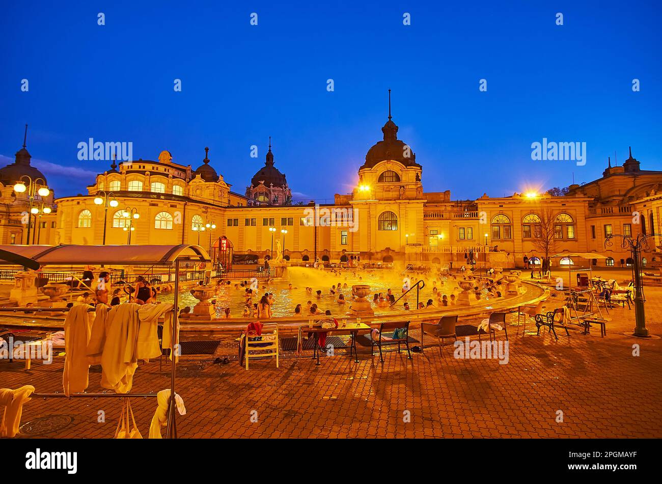BUDAPEST, UNGARN - 22. FEBRUAR 2022: Der Innenhof mit Thermalbad im Freien der Szechenyi-Thermalbäder in heller Abendbeleuchtung, am 22. Februar in Buda Stockfoto