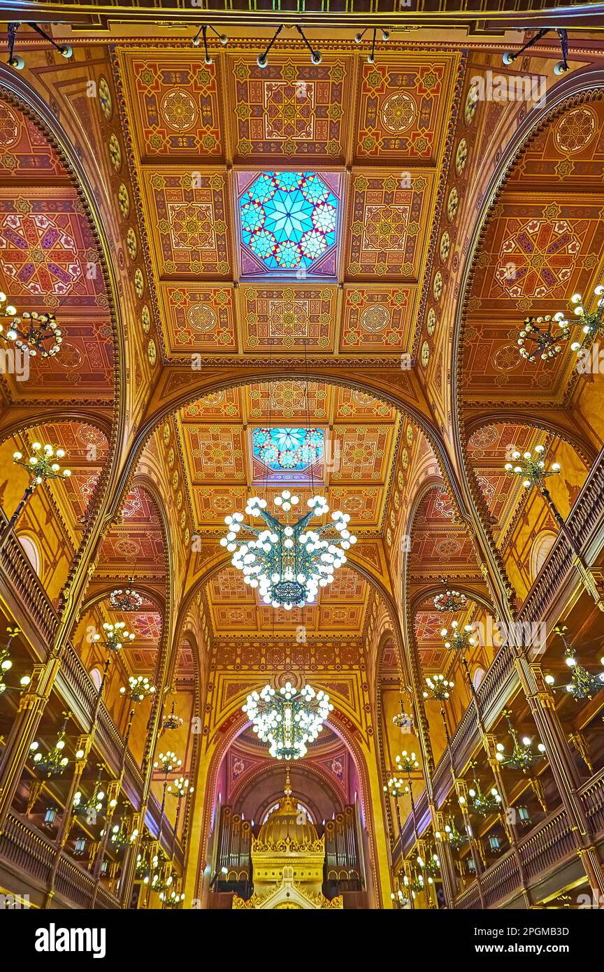 BUDAPEST, UNGARN - 22. FEBRUAR 2022: Die reich verzierte Decke der Dohany Street Synagoge mit traditionellen geometrischen Mustern, Buntglasfenstern A. Stockfoto