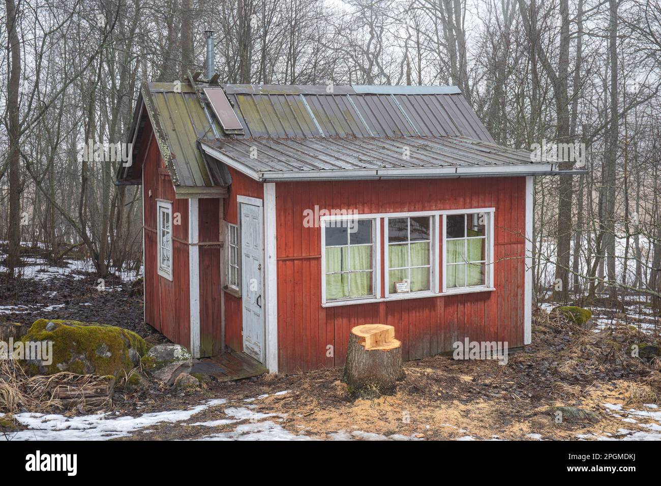 Kleine Hütte aus rotem Ocker auf der Insel Kuusiluoto an einem nebligen frühen Frühlingstag. Helsinki, Finnland. Stockfoto