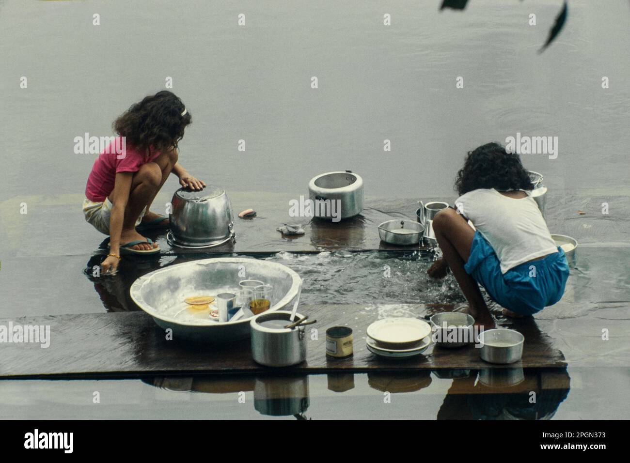 Das tägliche Leben im Dorf des brasilianischen Amazonas, Kinder waschen das Geschirr am nahegelegenen Fluss. Stockfoto