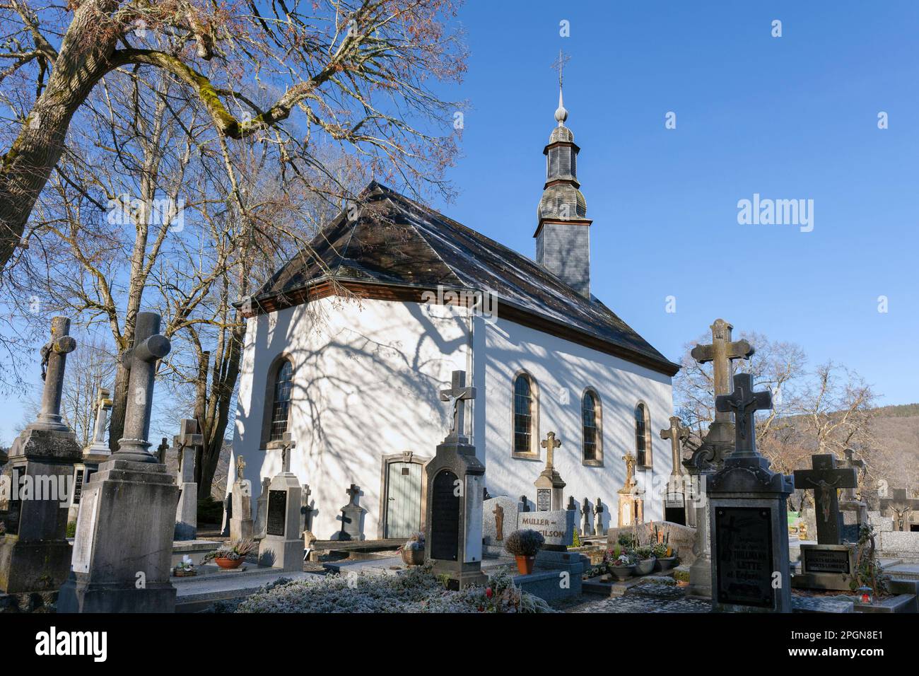 Europa, Luxemburg, Diekirch, Esch-sur-Sure, Kapelle Ste-Croix mit Bäumen und Gräbern im Winter Stockfoto