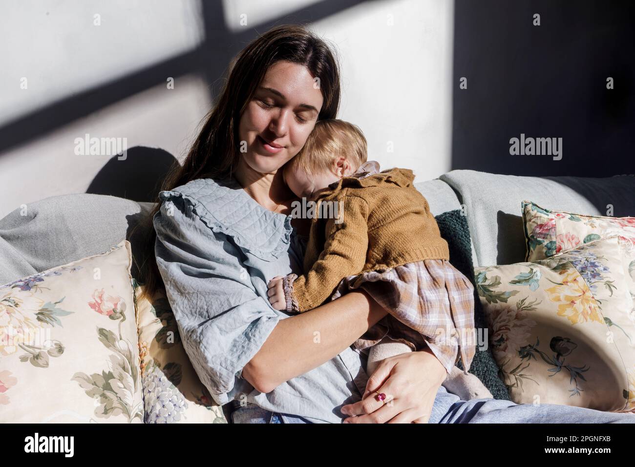 Mutter mit Baby-Mädchen, die sich zu Hause auf dem Sofa entspannen Stockfoto