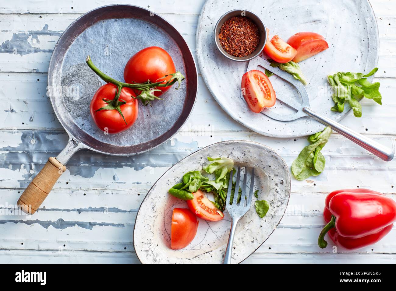 Chilipulver und rohes Gemüse auf Tellern und Bratpfanne Stockfoto