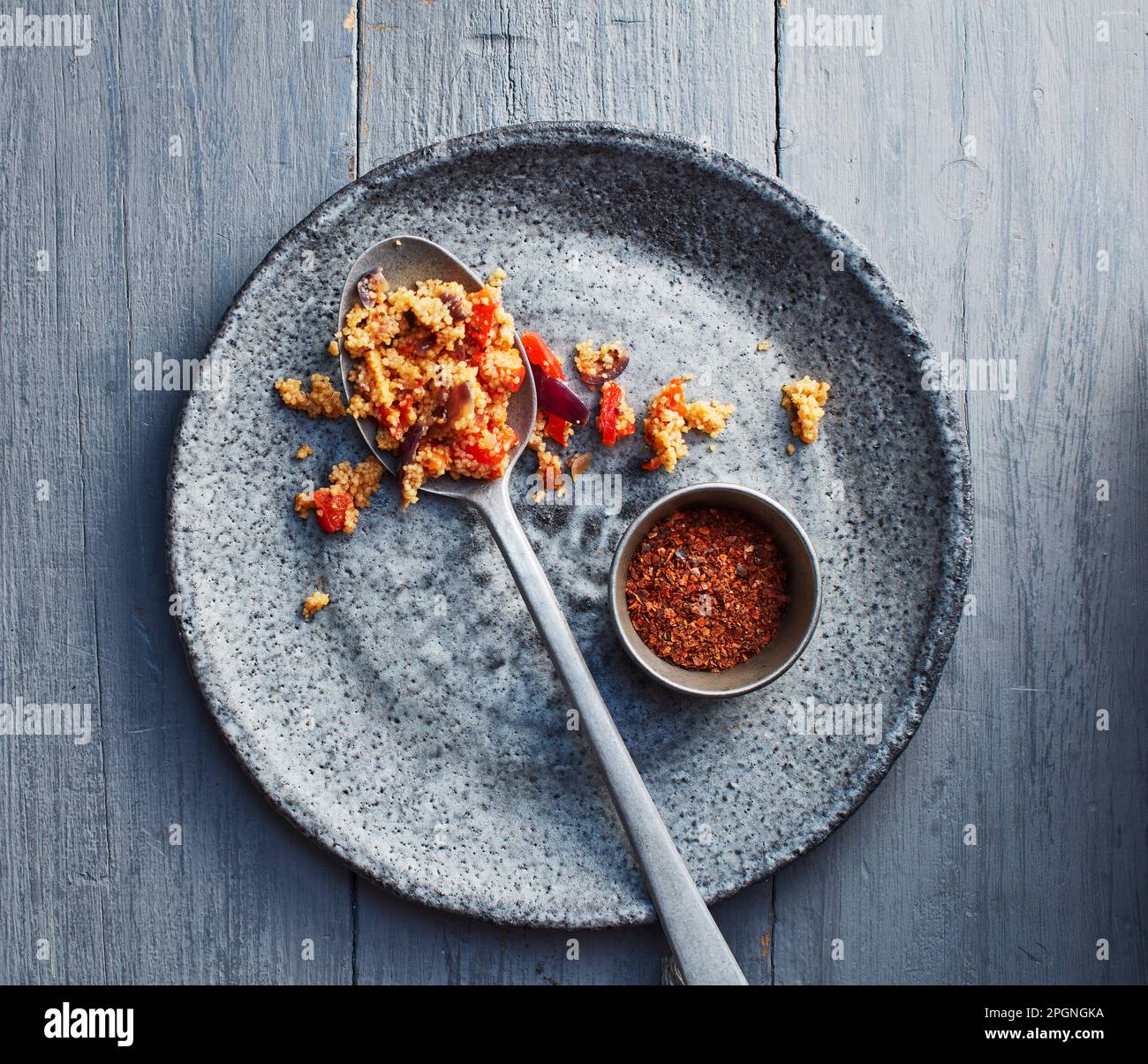 Chilipulver und Teller mit halb gefressenem Couscous Stockfoto