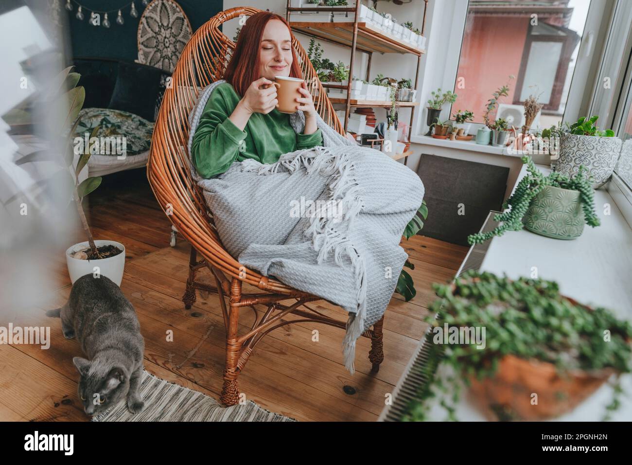 Eine Frau, die zu Hause auf einem Stuhl sitzt und Kaffee genießt Stockfoto
