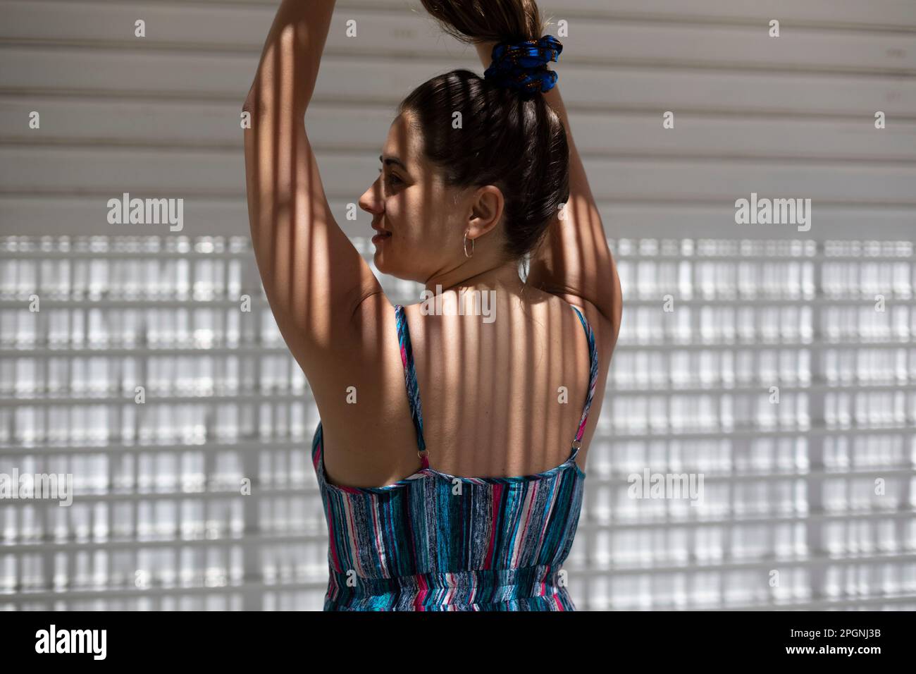 Junge Frau mit erhobenen Armen und Blick auf die Wand Stockfoto