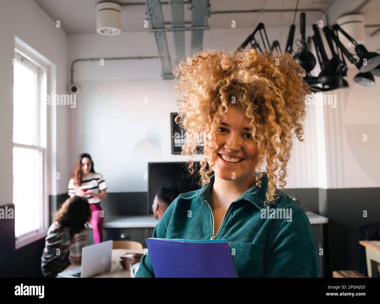 Glückliche Geschäftsfrau mit lockigen Haaren im Büro Stockfoto