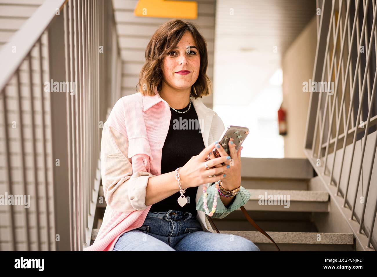 Frau mit Smartphone, die auf der Treppe sitzt Stockfoto
