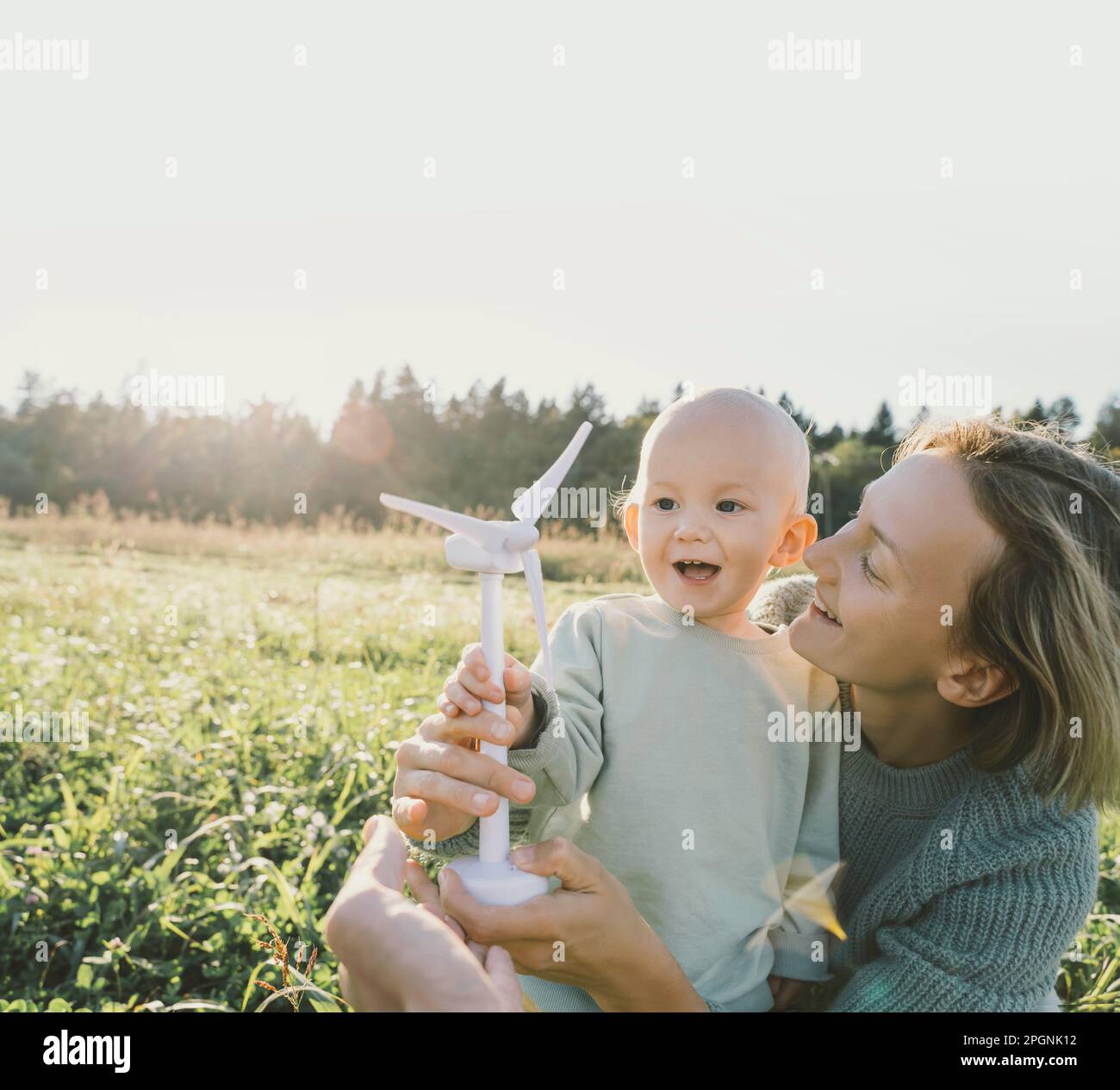 Fröhliche Mutter, die mit ihrem Sohn spielt und ein Windturbinenmodell hält Stockfoto