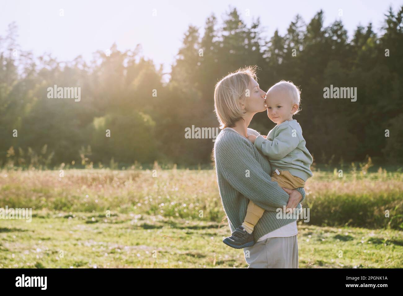 Mutter küsst Sohn an einem sonnigen Tag Stockfoto