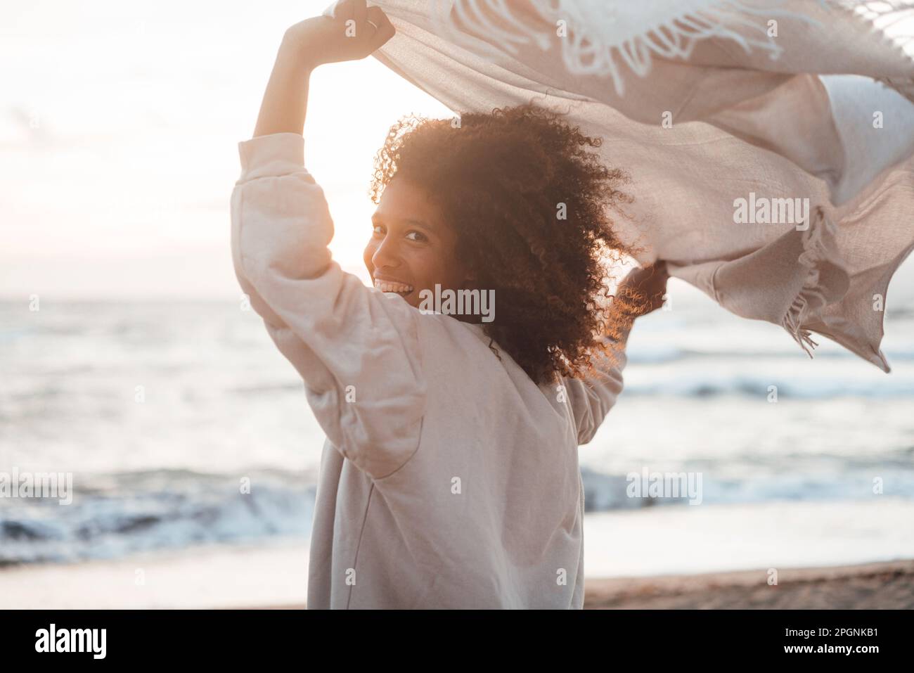 Fröhliche junge Frau mit Schal am Strand Stockfoto