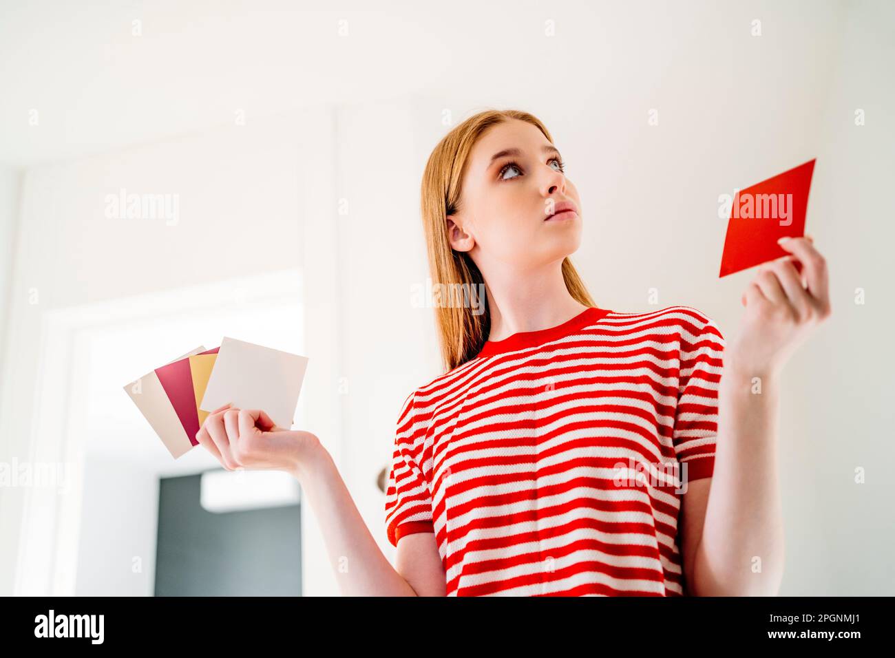 Ein aufmerksames Mädchen, das zu Hause Farbmuster hält Stockfoto