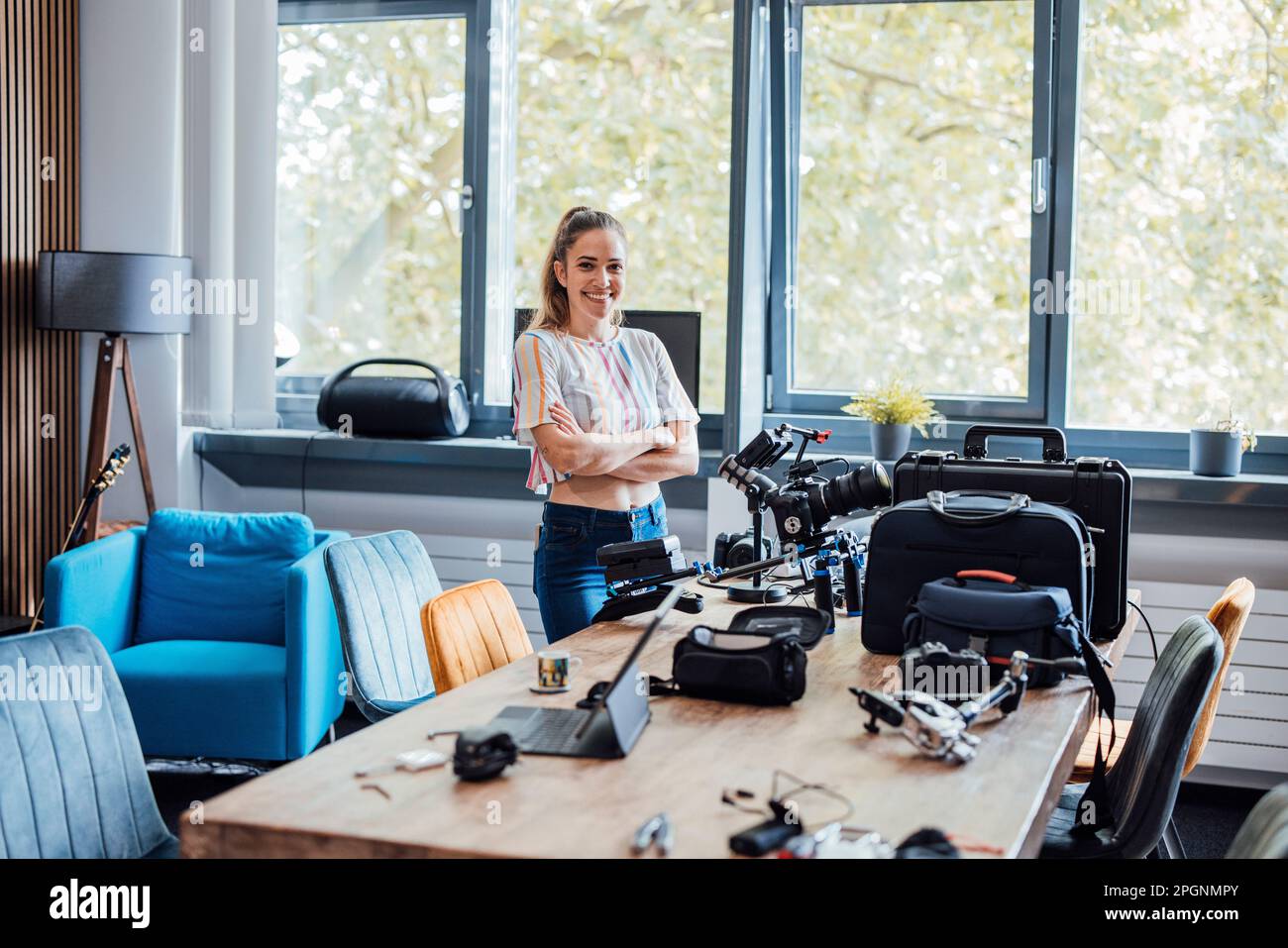 Glückliche Geschäftsfrau mit Kamera und Ausstattung auf dem Schreibtisch Stockfoto