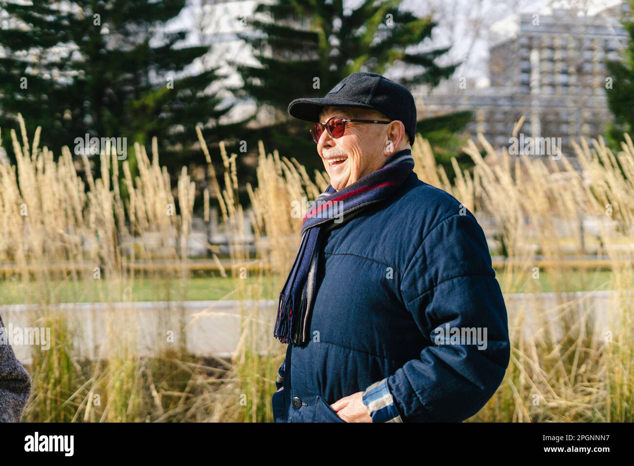 Ein glücklicher Senior-Mann, der im Park eine Jacke trägt Stockfoto