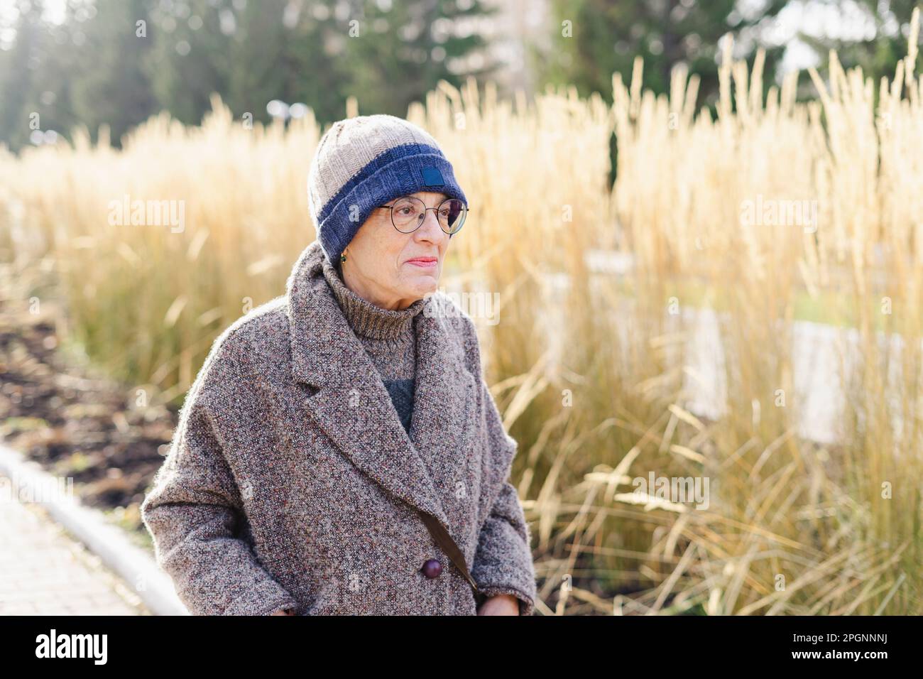 Seniorin in warmer Kleidung, die im Park spaziert Stockfoto