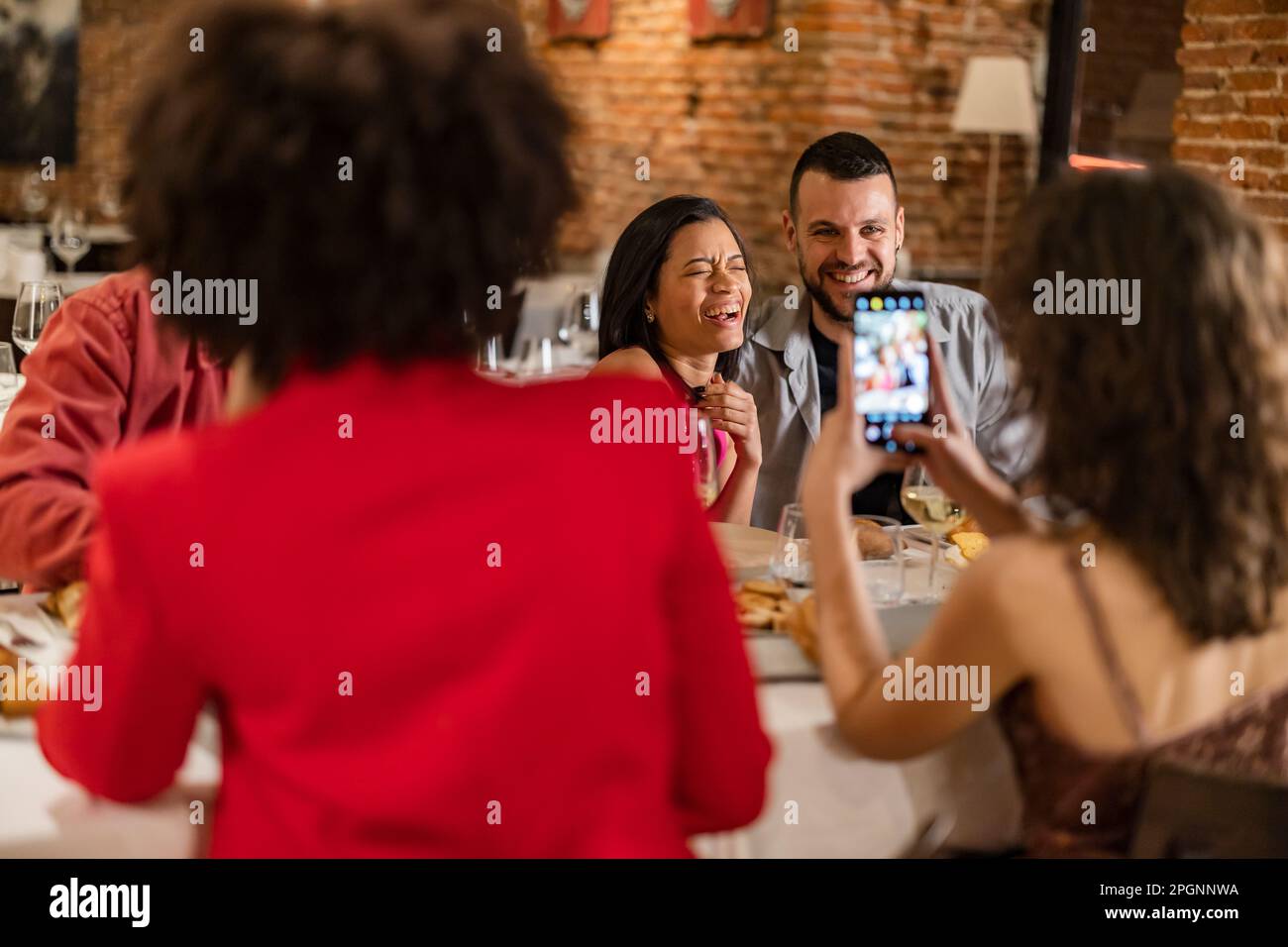 Frau, die Bilder von Freunden mit dem Smartphone aufnimmt Stockfoto