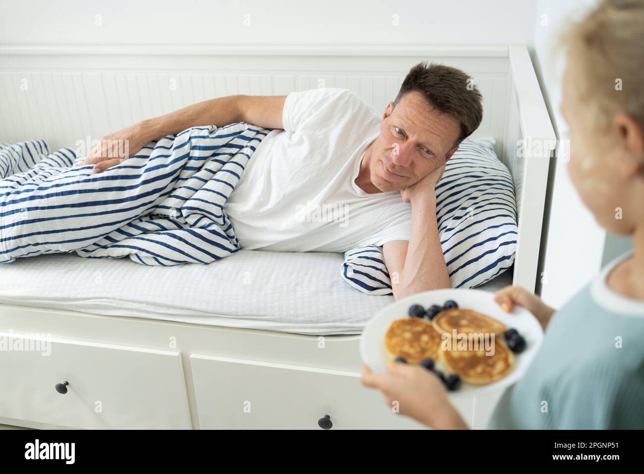 Ein Mädchen, das Pfannkuchen für Vater servierte, lag zu Hause im Bett Stockfoto