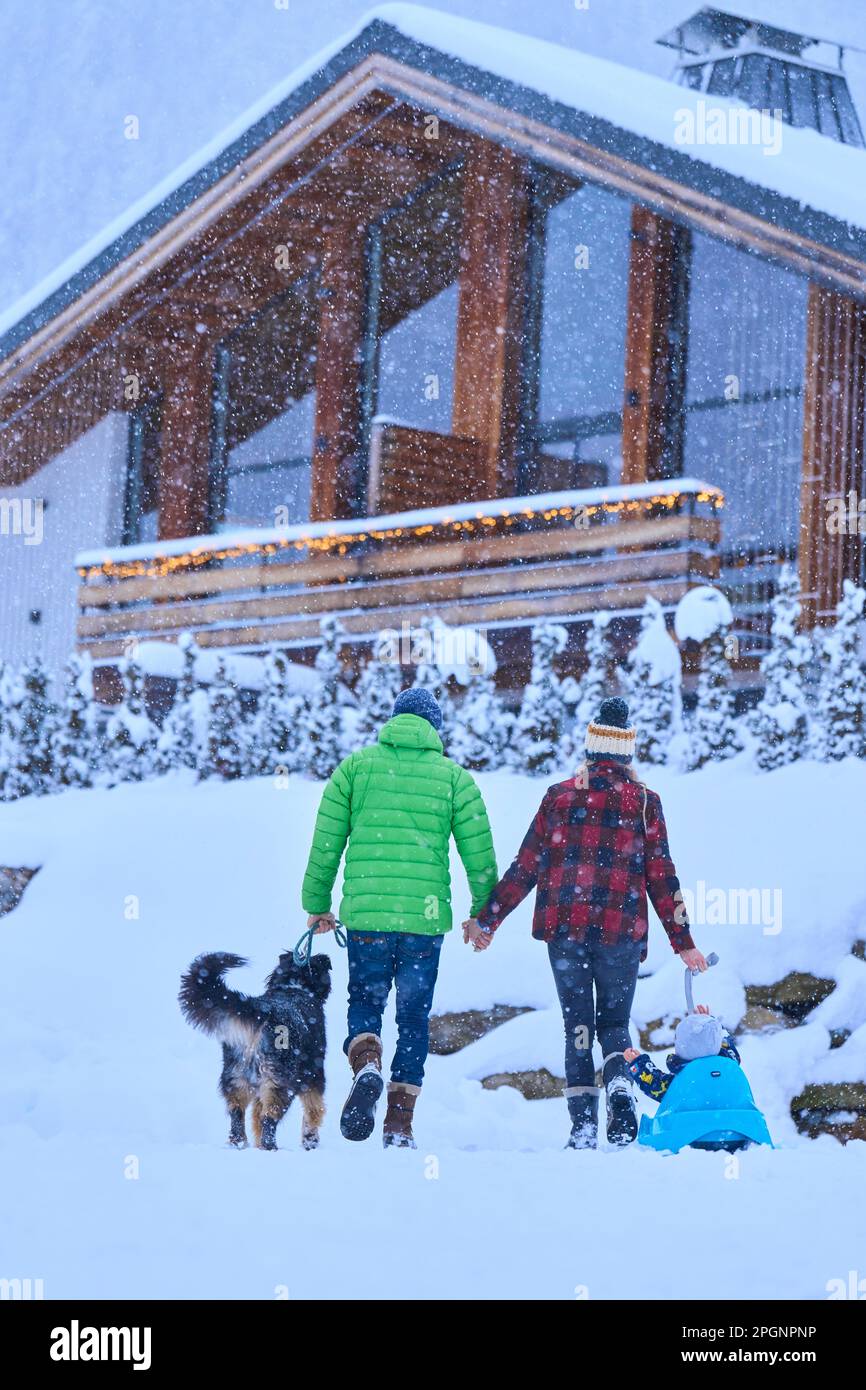Eltern mit Sohn und Hund, die im Schnee laufen Stockfoto
