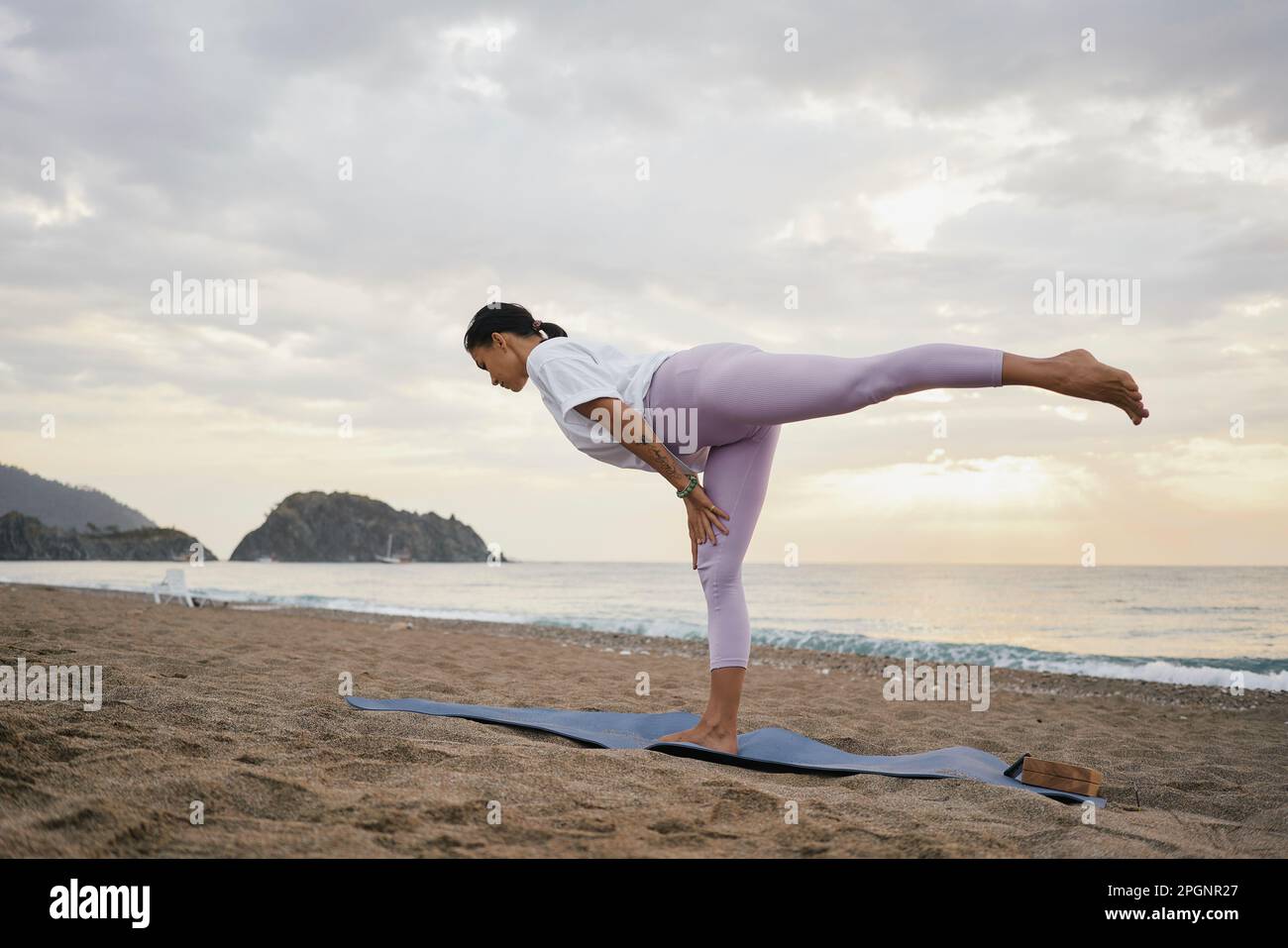 Eine Frau, die morgens am Strand Yoga praktiziert Stockfoto