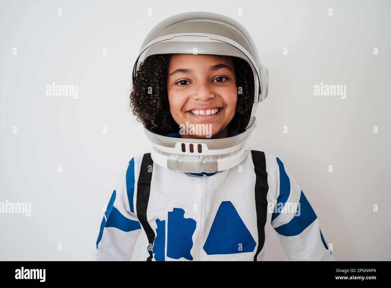 Glückliches Mädchen, das Astronautenkostüm vor der weißen Wand trägt Stockfoto