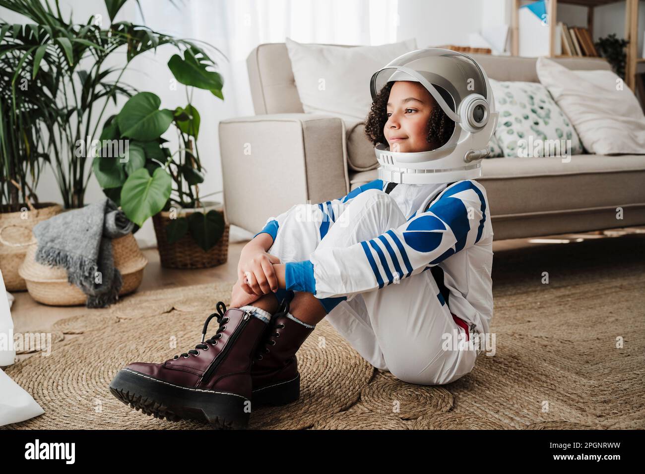 Ein rücksichtsvolles Mädchen, das zu Hause einen Weltraumhelm trägt Stockfoto